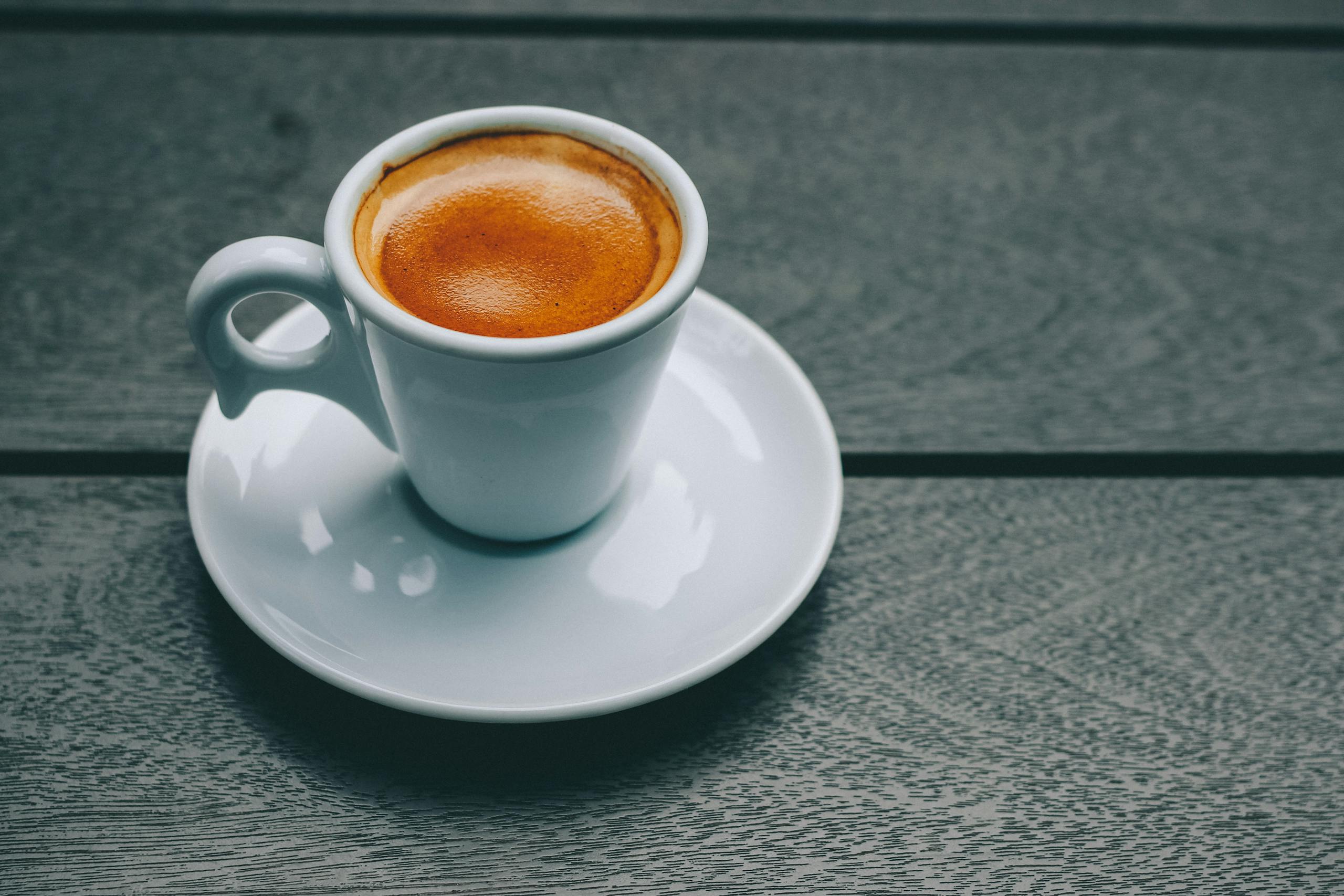 A stylish espresso in a porcelain cup on a wooden table, perfect for coffee lovers.
