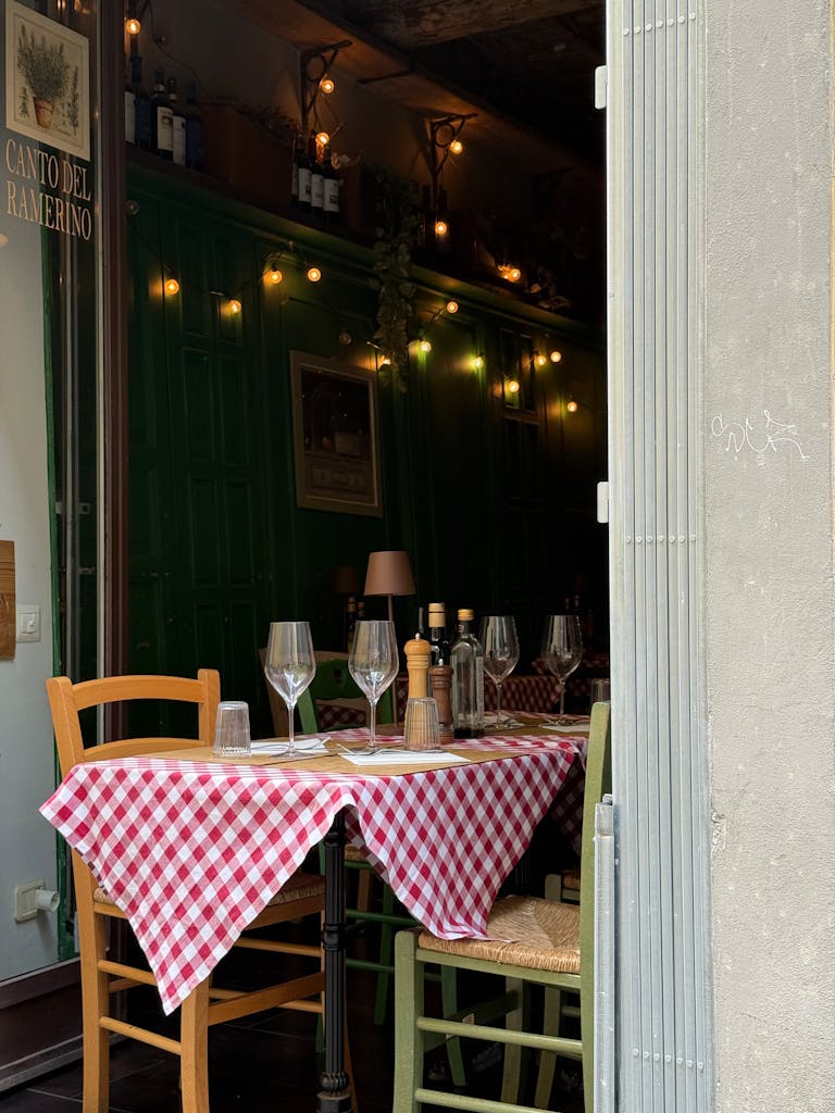 Charming Italian cafe setting with checkered tablecloth and empty wine glasses, inviting ambiance in Florence.